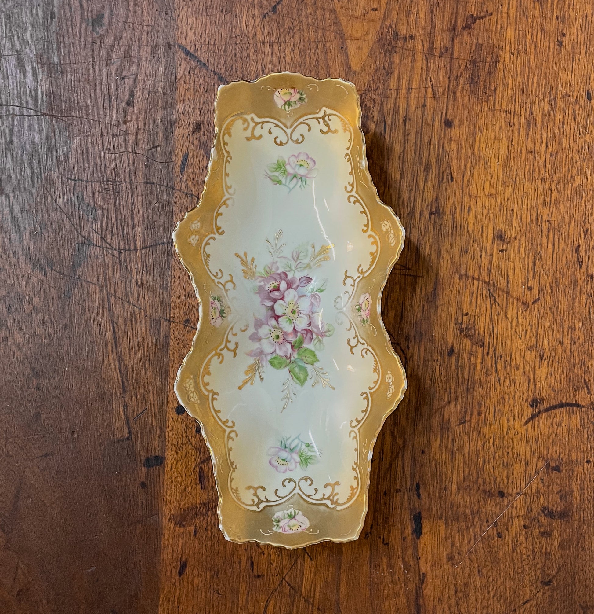 Decorative ceramic tray with floral patterns on a wooden surface