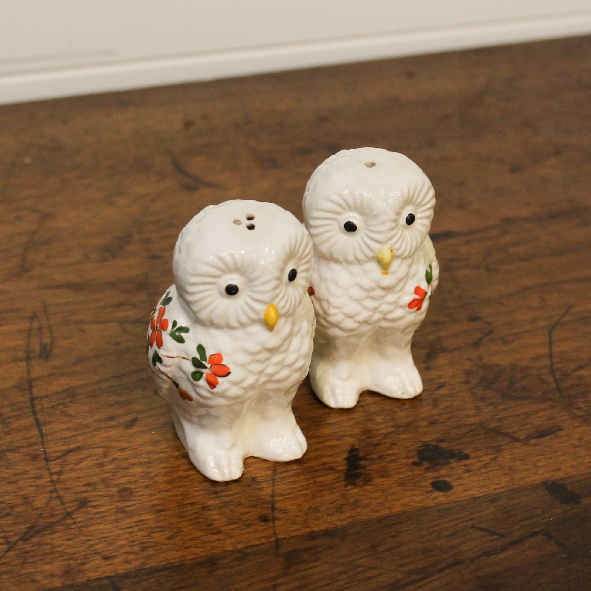 Two owl-shaped salt and pepper shakers on a wooden surface.