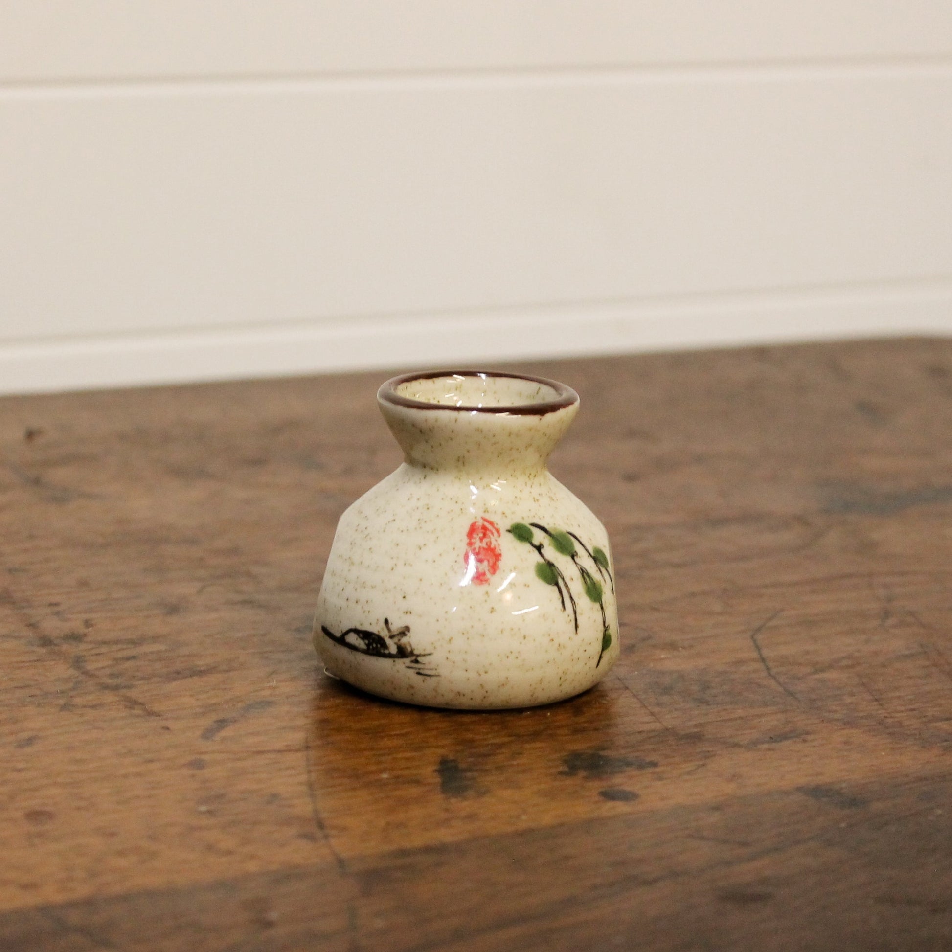 Small ceramic vase with floral design on a wooden surface