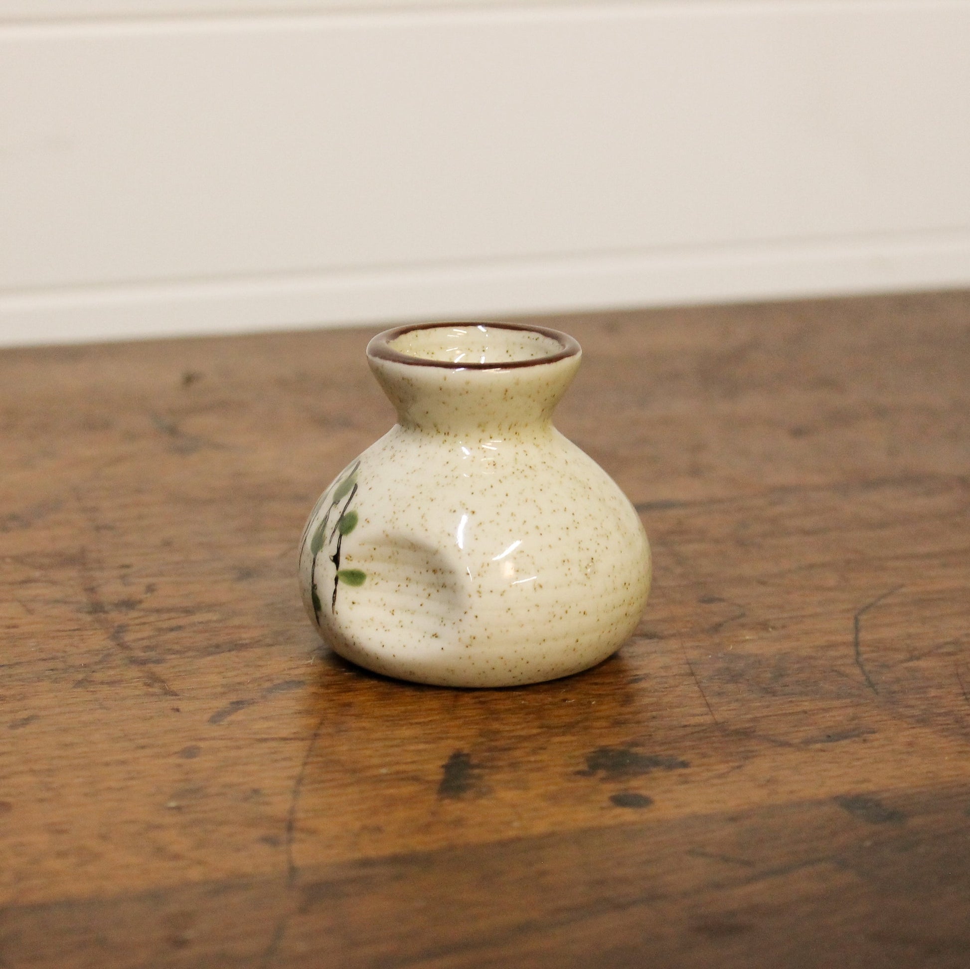 Small ceramic vase on a wooden surface with a plain background