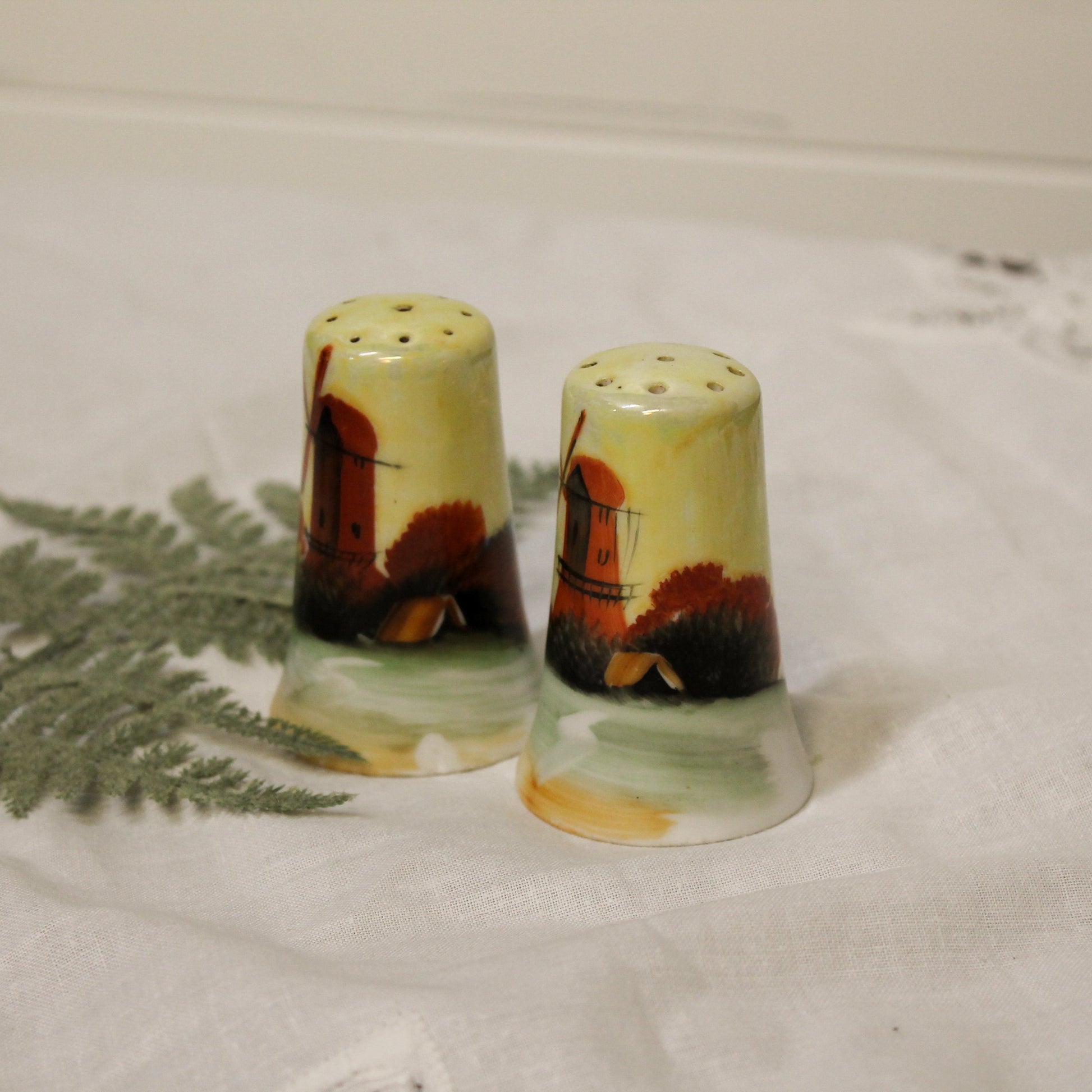 Two ceramic salt and pepper shakers with artistic design on a textured surface.