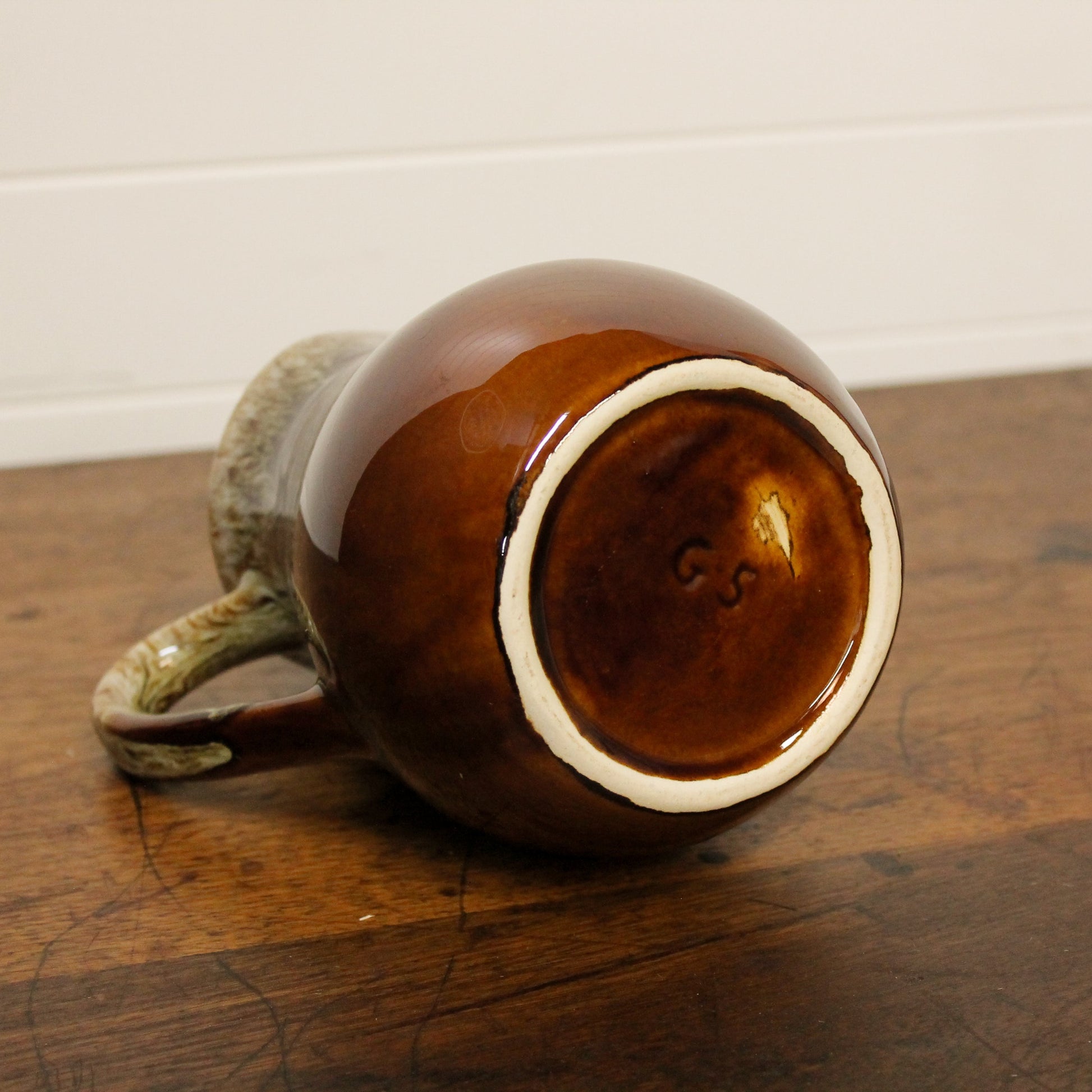 Brown ceramic pitcher with a white rim on a wooden surface