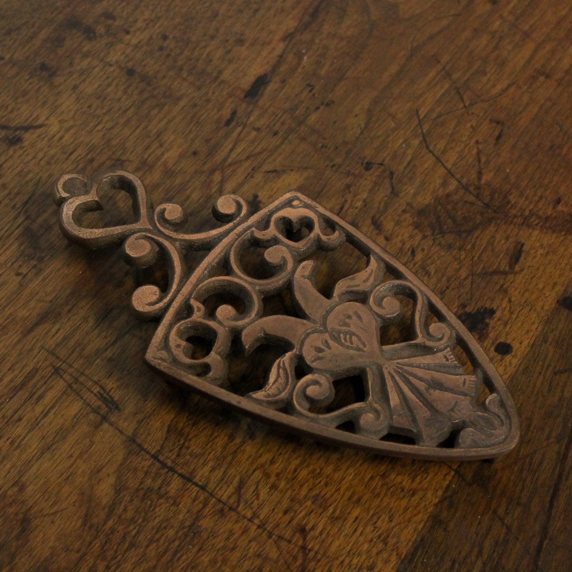 Decorative copper trivet with intricate patterns on a wooden surface