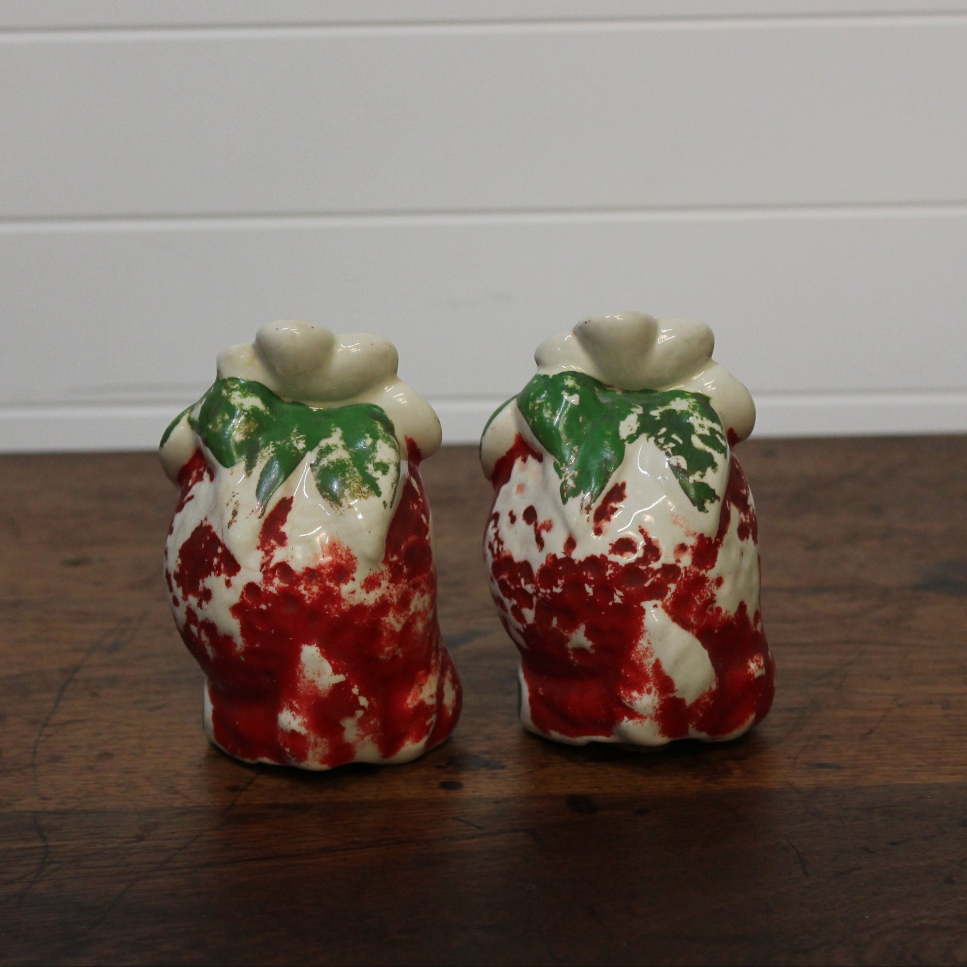 Two ceramic salt and pepper shakers with a floral design on a wooden surface.