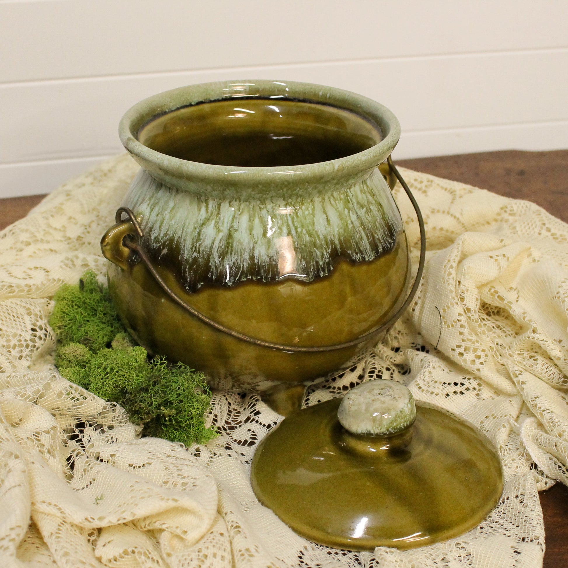 Vintage-style green ceramic pot with lid on a lace tablecloth