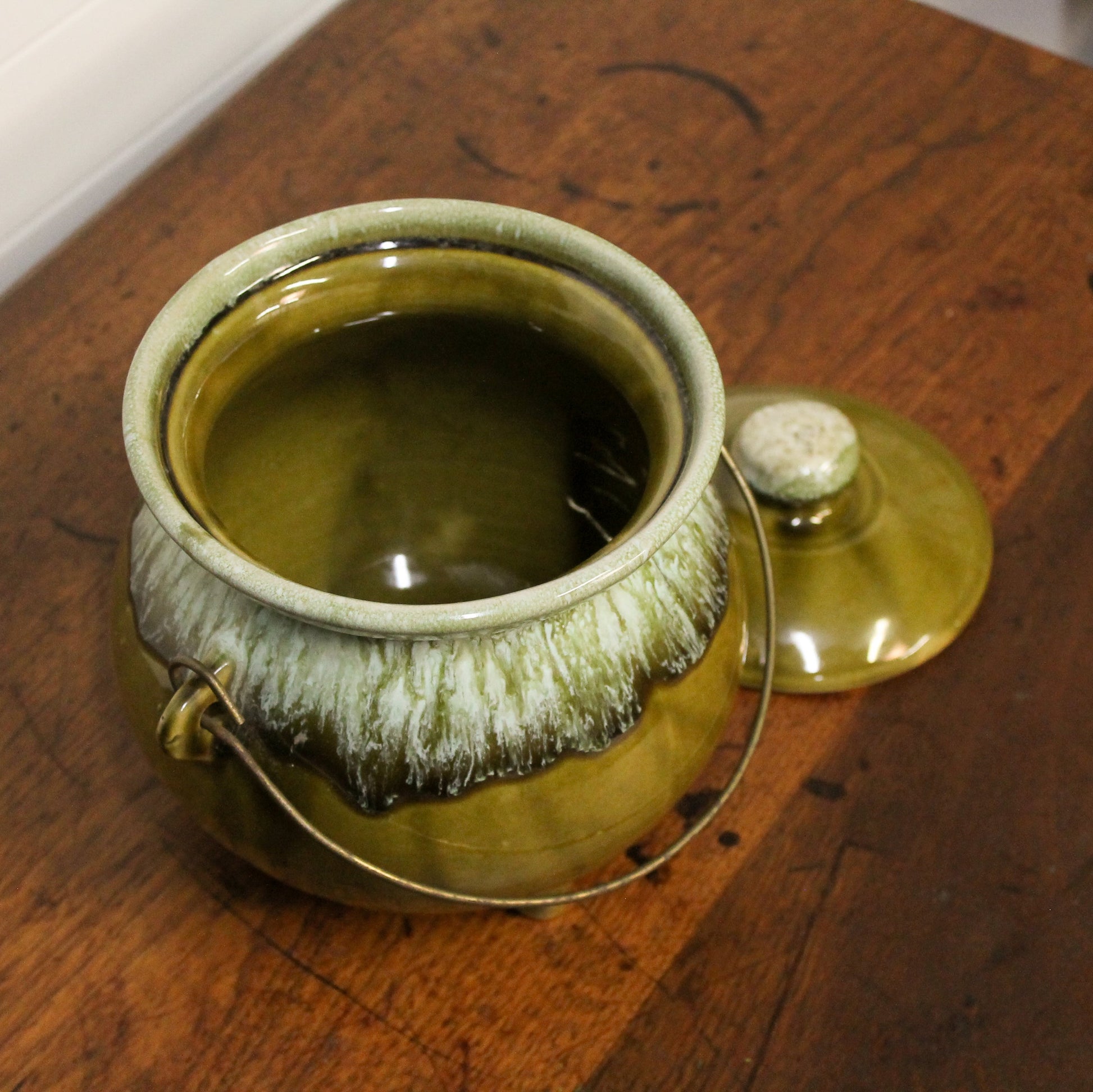 Green ceramic jar with lid on a wooden surface