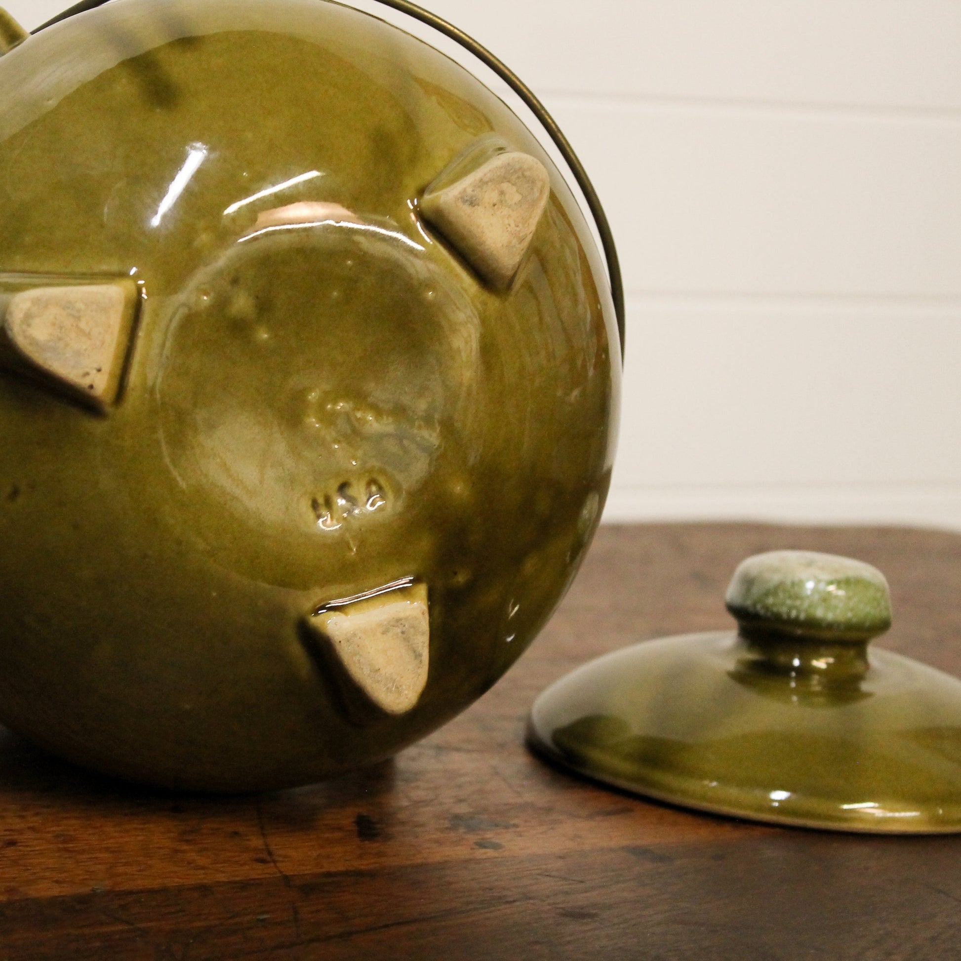 Green ceramic pot with lid on a wooden surface
