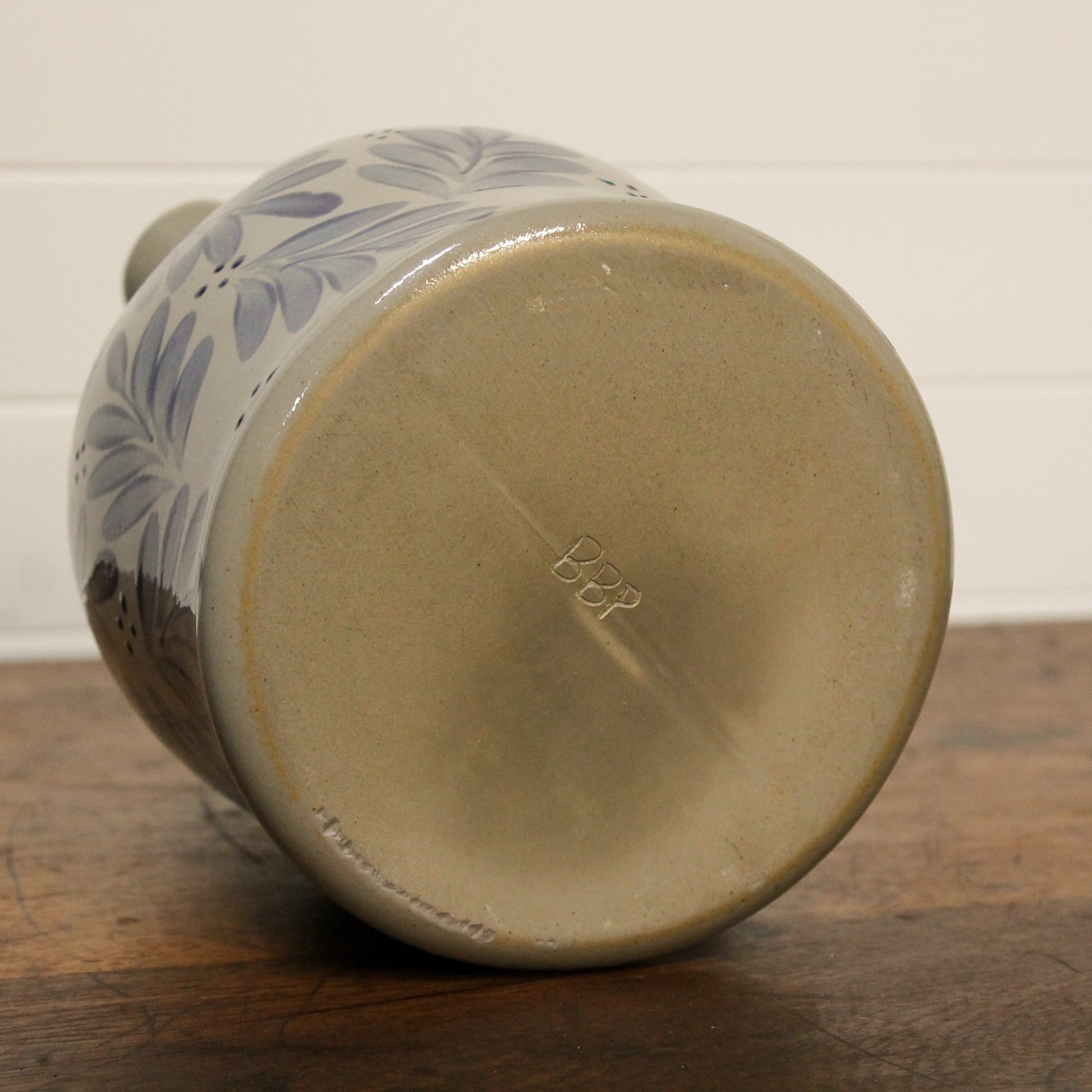 Ceramic pitcher with floral design on a wooden surface