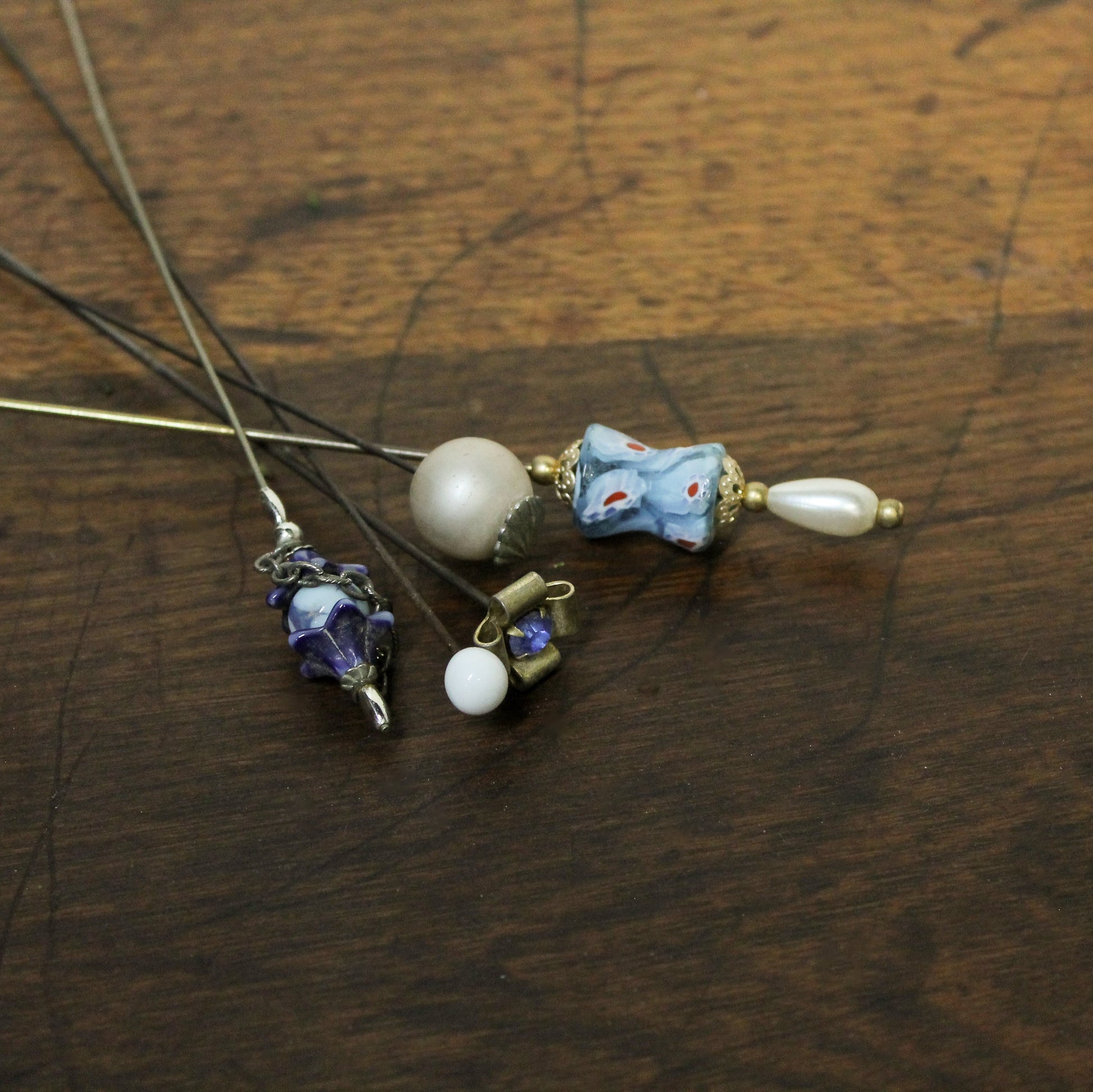 Decorative hairpin with pearls and floral elements on a wooden surface