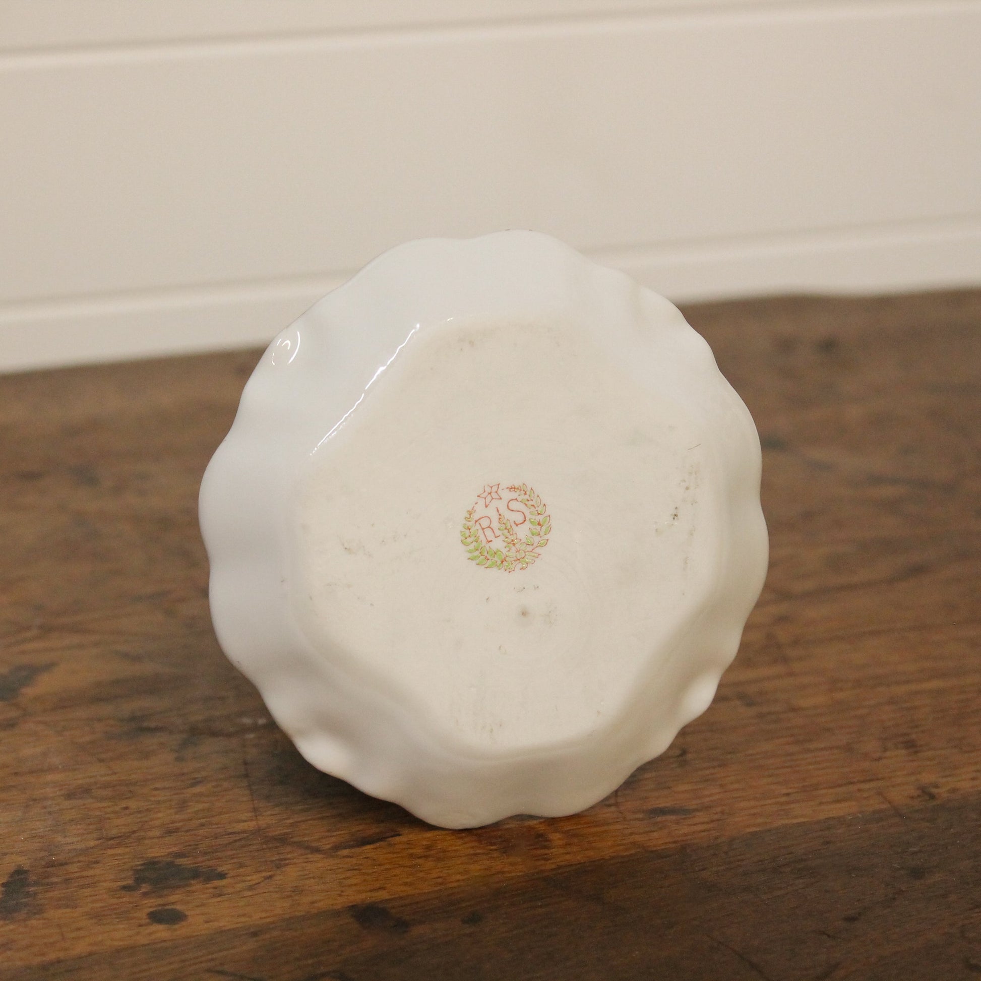 White ceramic object with a logo on a wooden surface