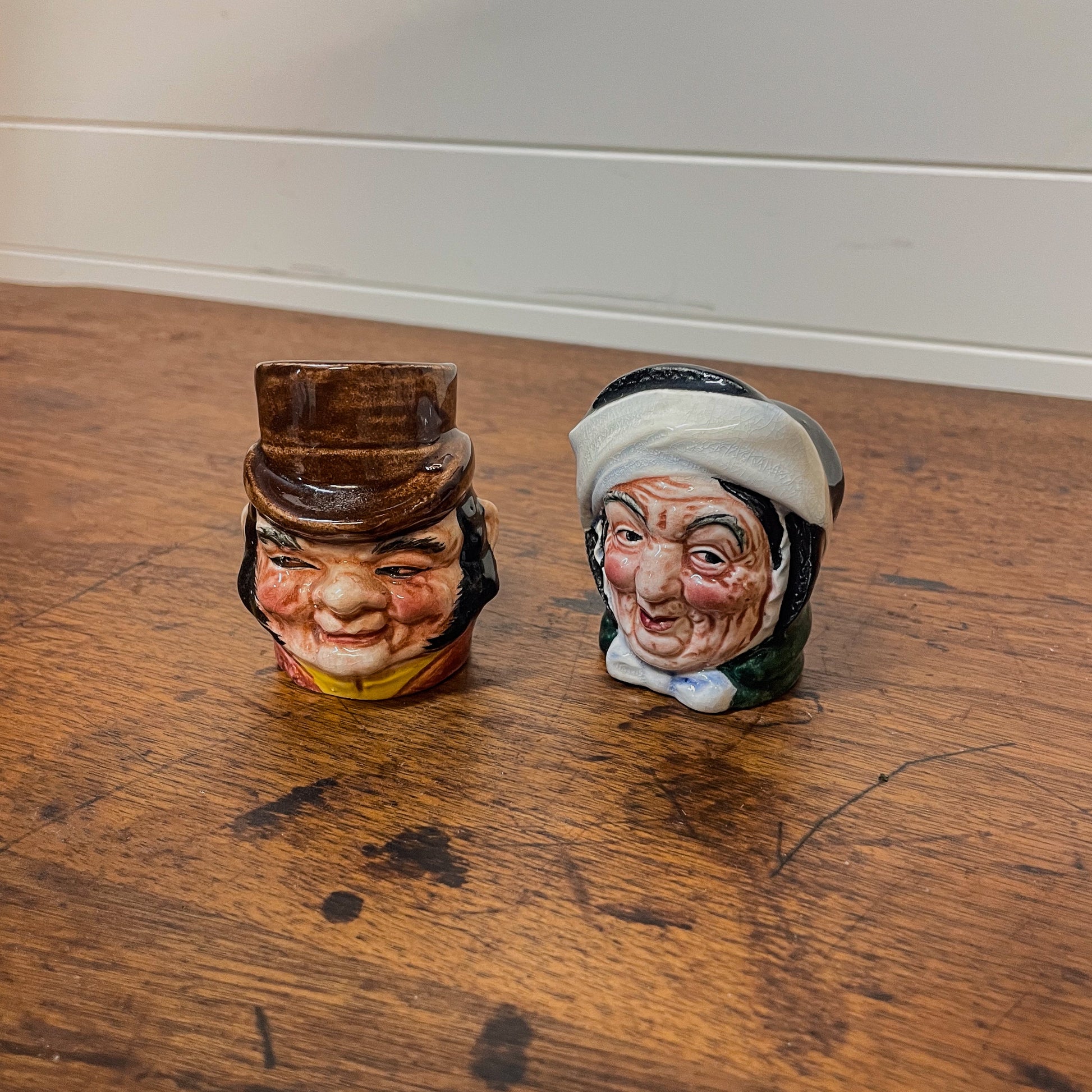 Two vintage ceramic character heads on a wooden surface