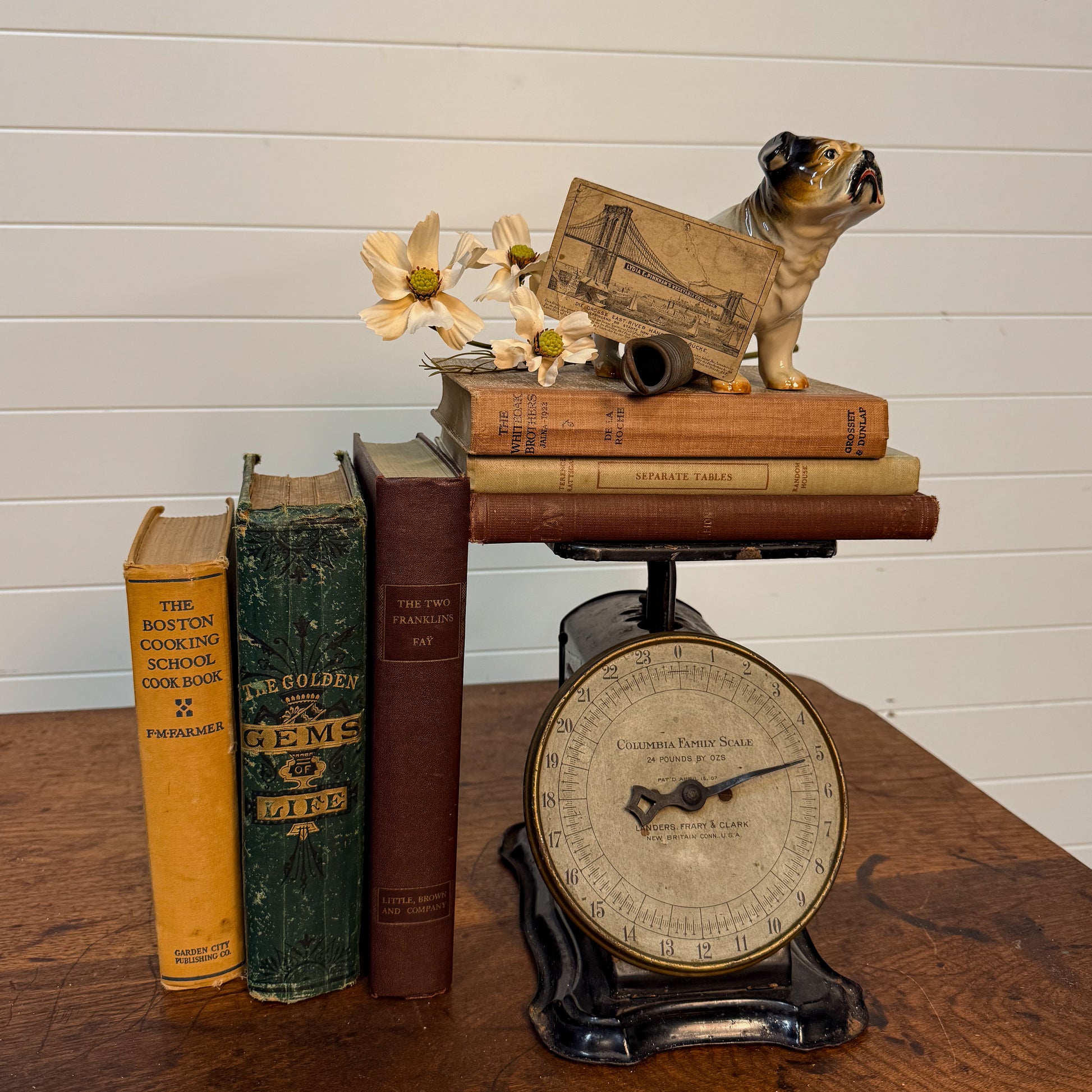Vintage scale with books and a small dog figurine on a wooden surface.