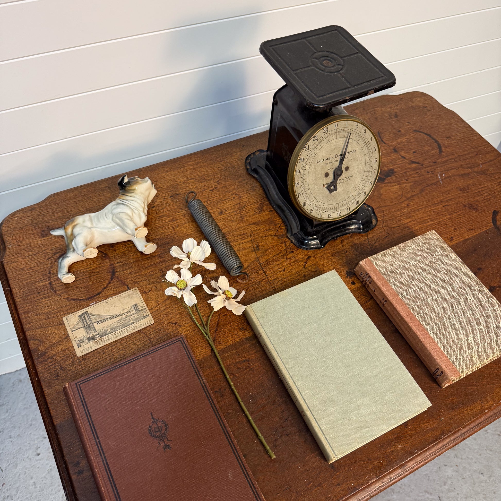 Vintage items including a scale, books, and a figurine on a wooden surface.