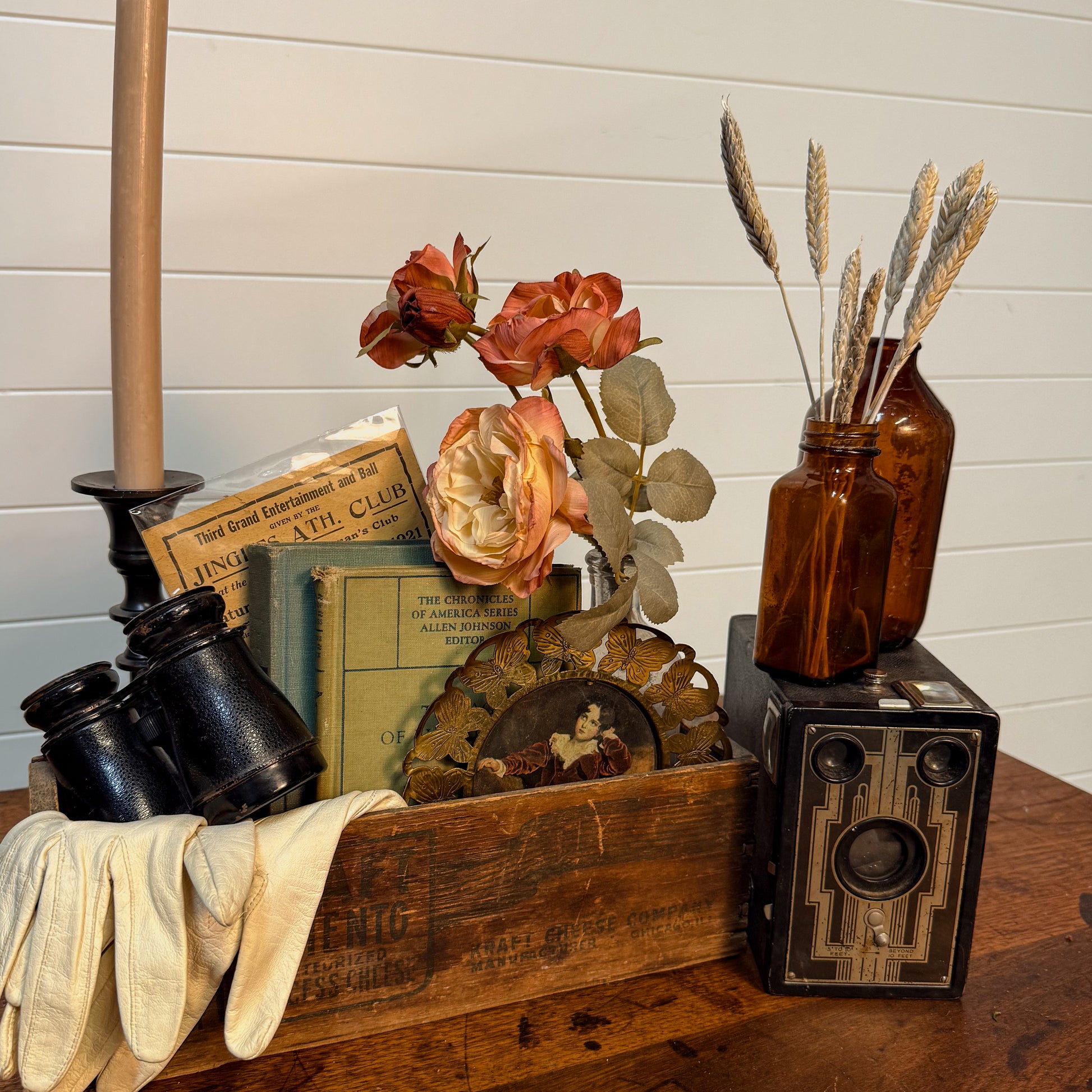 Vintage-style display with books, camera, and flowers on a wooden surface.