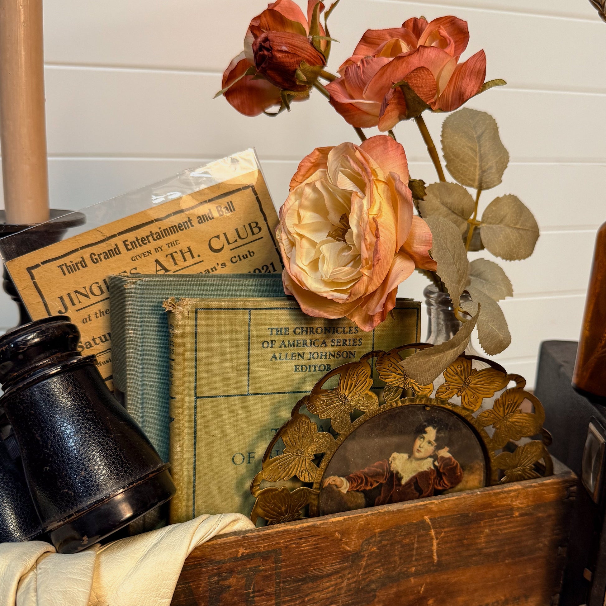 Vintage-style setup with books, flowers, and a camera on a wooden surface.