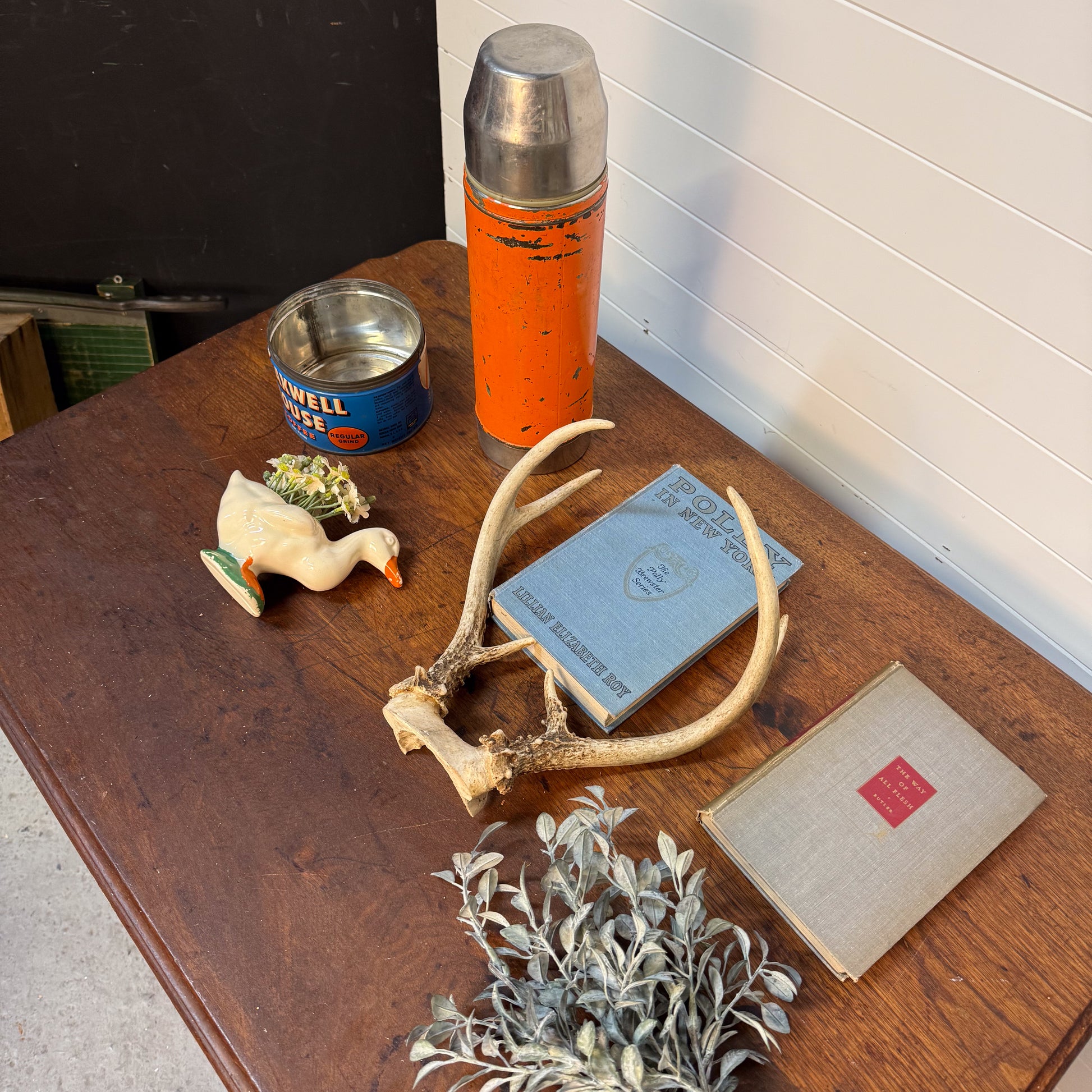 Collection of vintage items including a thermos, books, and decorative objects on a wooden surface.