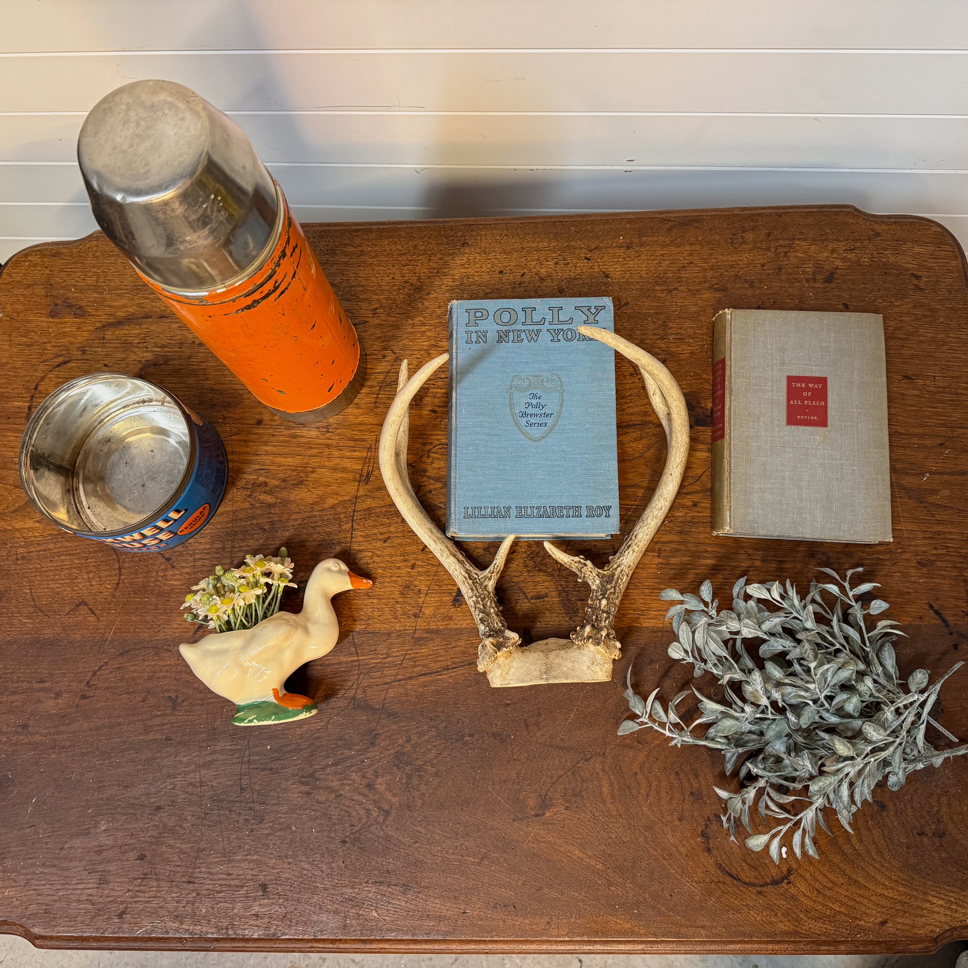Vintage items including a thermos, books, and decorative objects on a wooden surface.