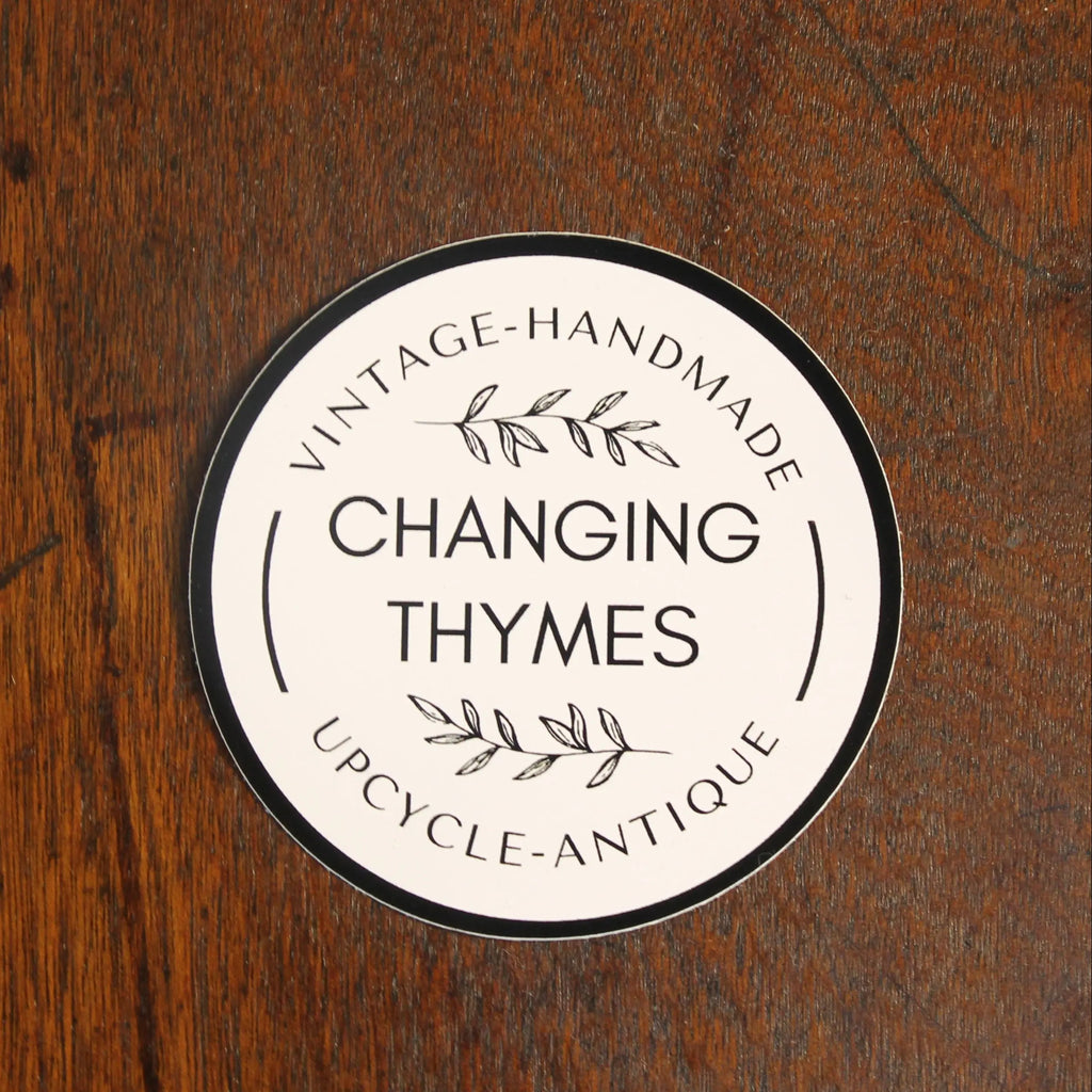 Round label with 'Changing Thymes' branding on a wooden surface