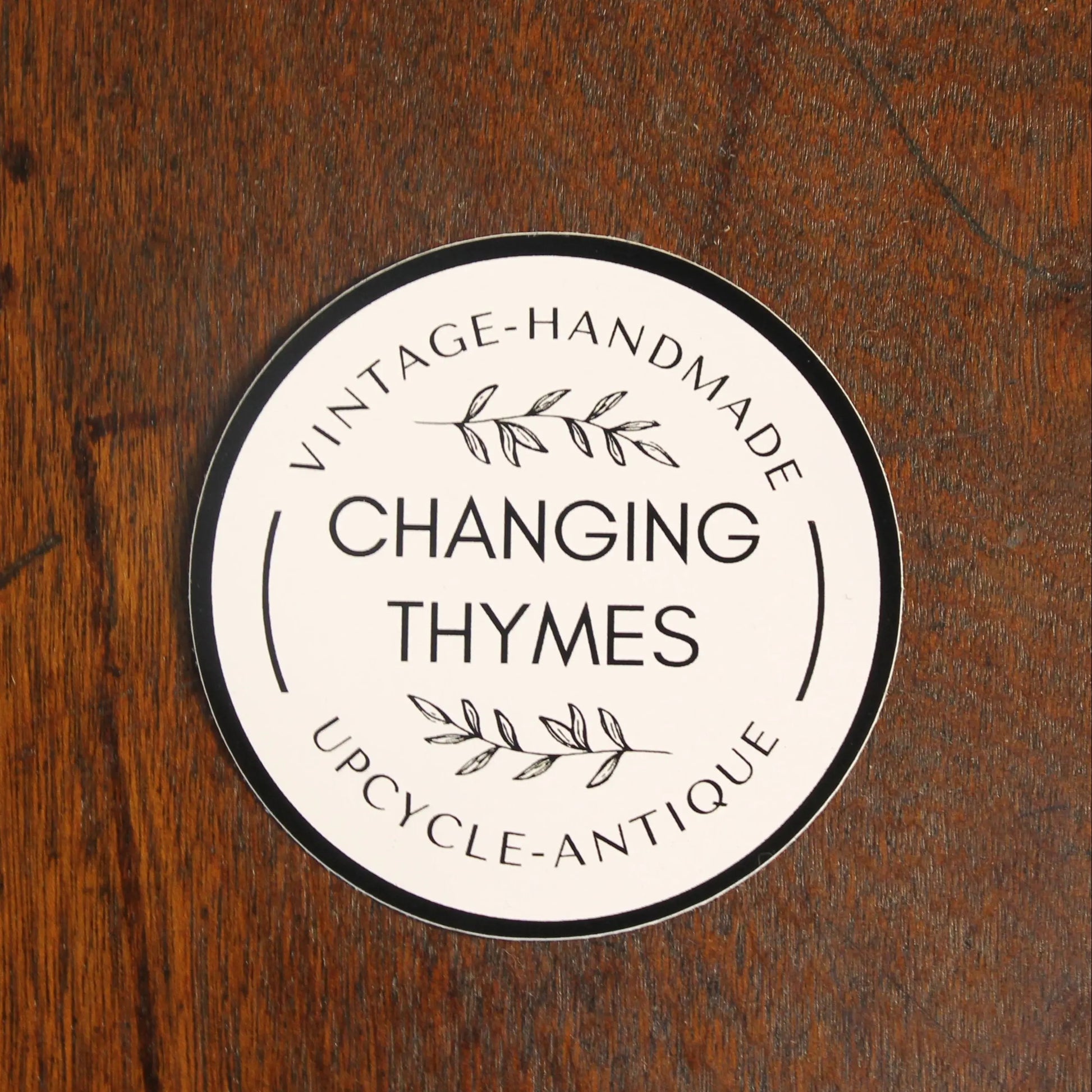 Round label with 'Changing Thymes' branding on a wooden surface
