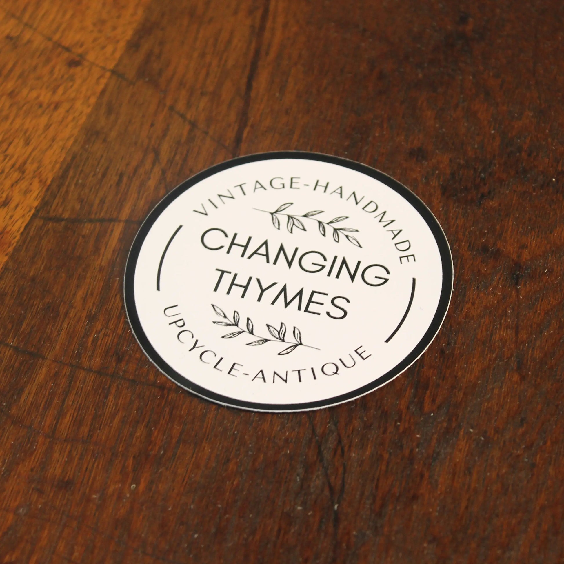 Round label with 'Changing Thymes' text on a wooden surface