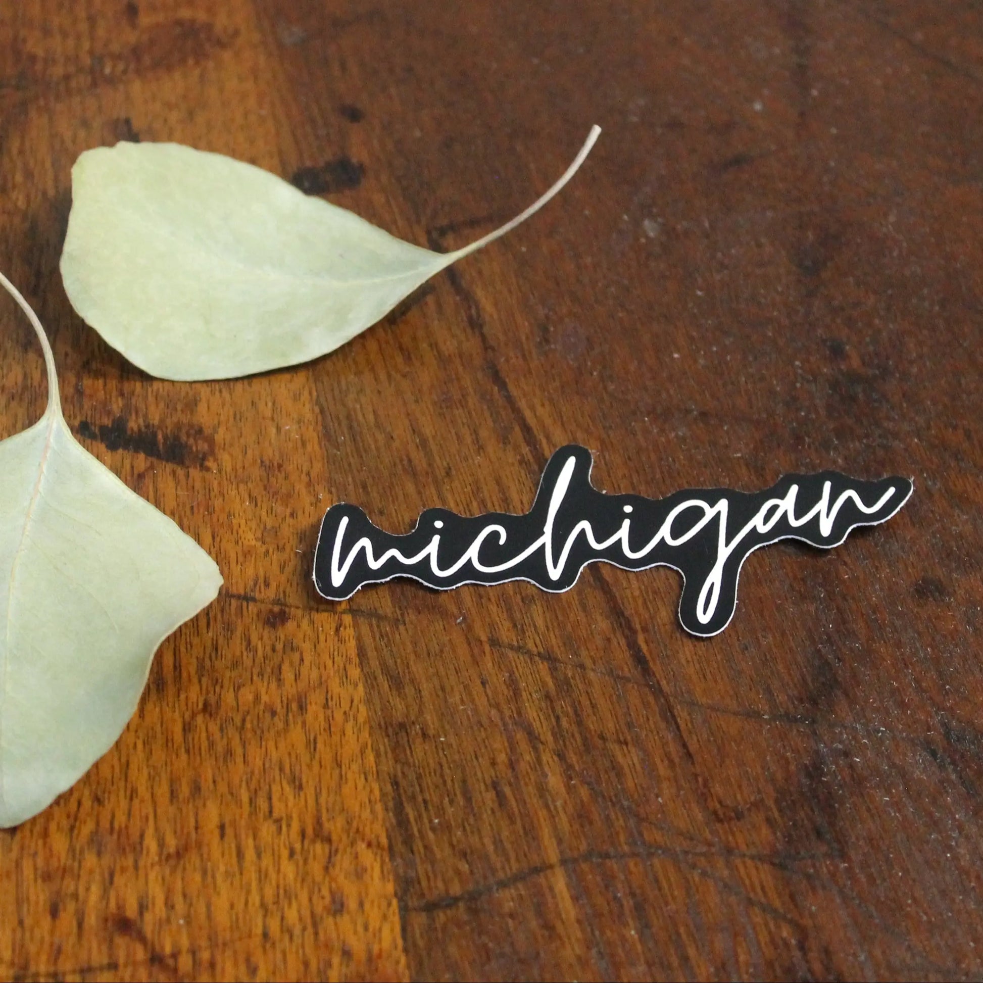 Two white leaves on a wooden surface with 'michigan' sticker.