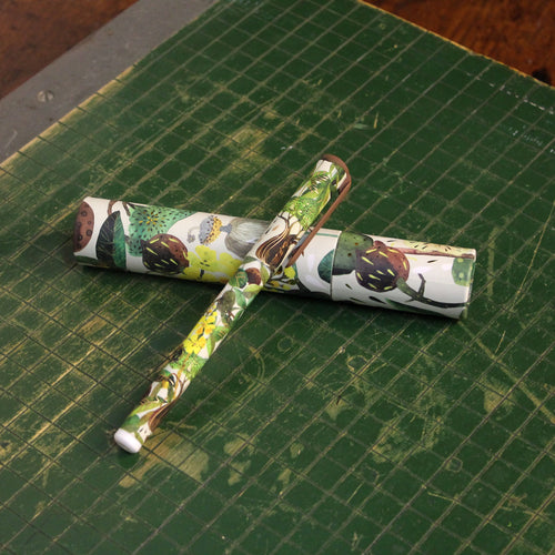 Pen sitting on top of its tubed case on a green cutting board