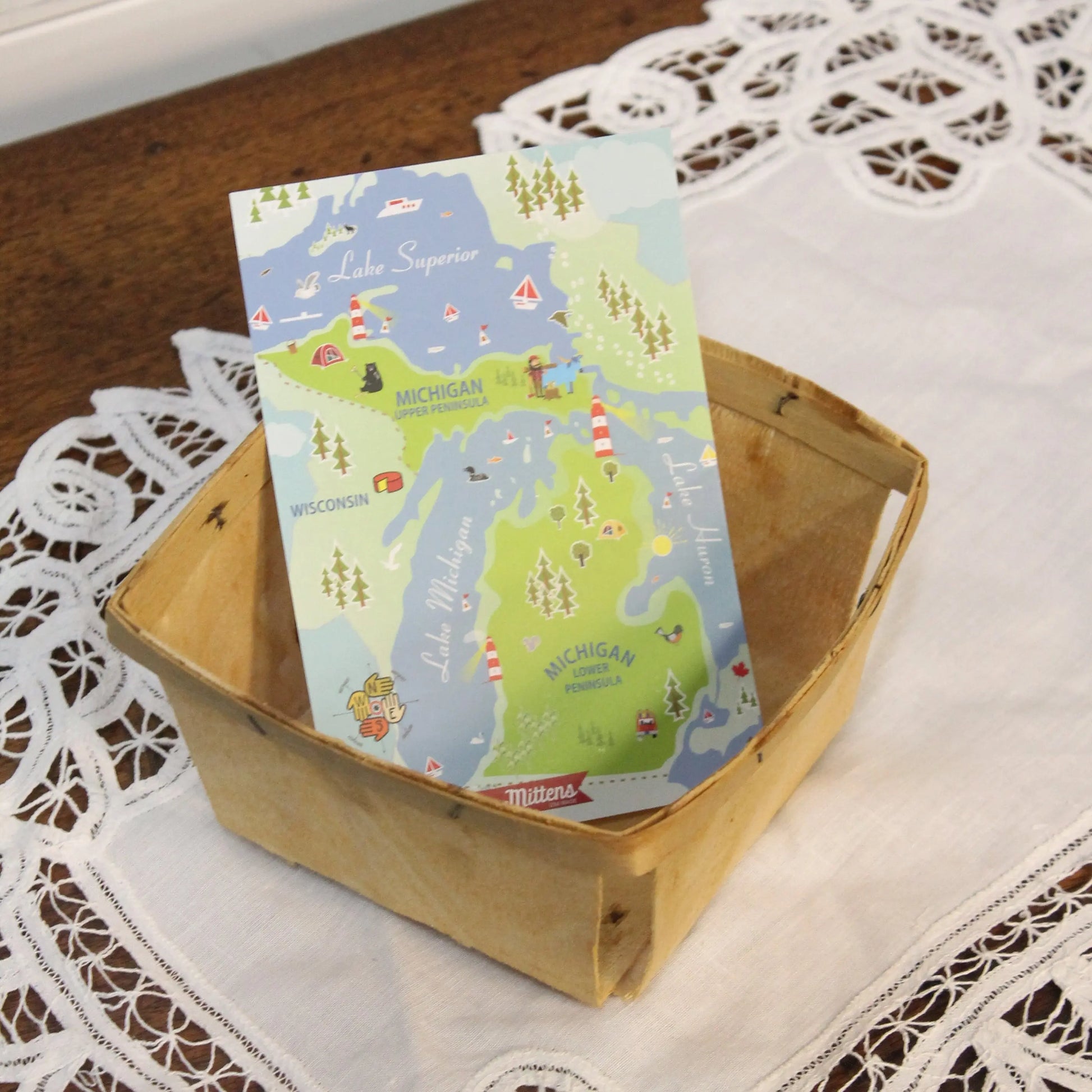 A Michigan Map Postcard in a wooden box sitting on lace.