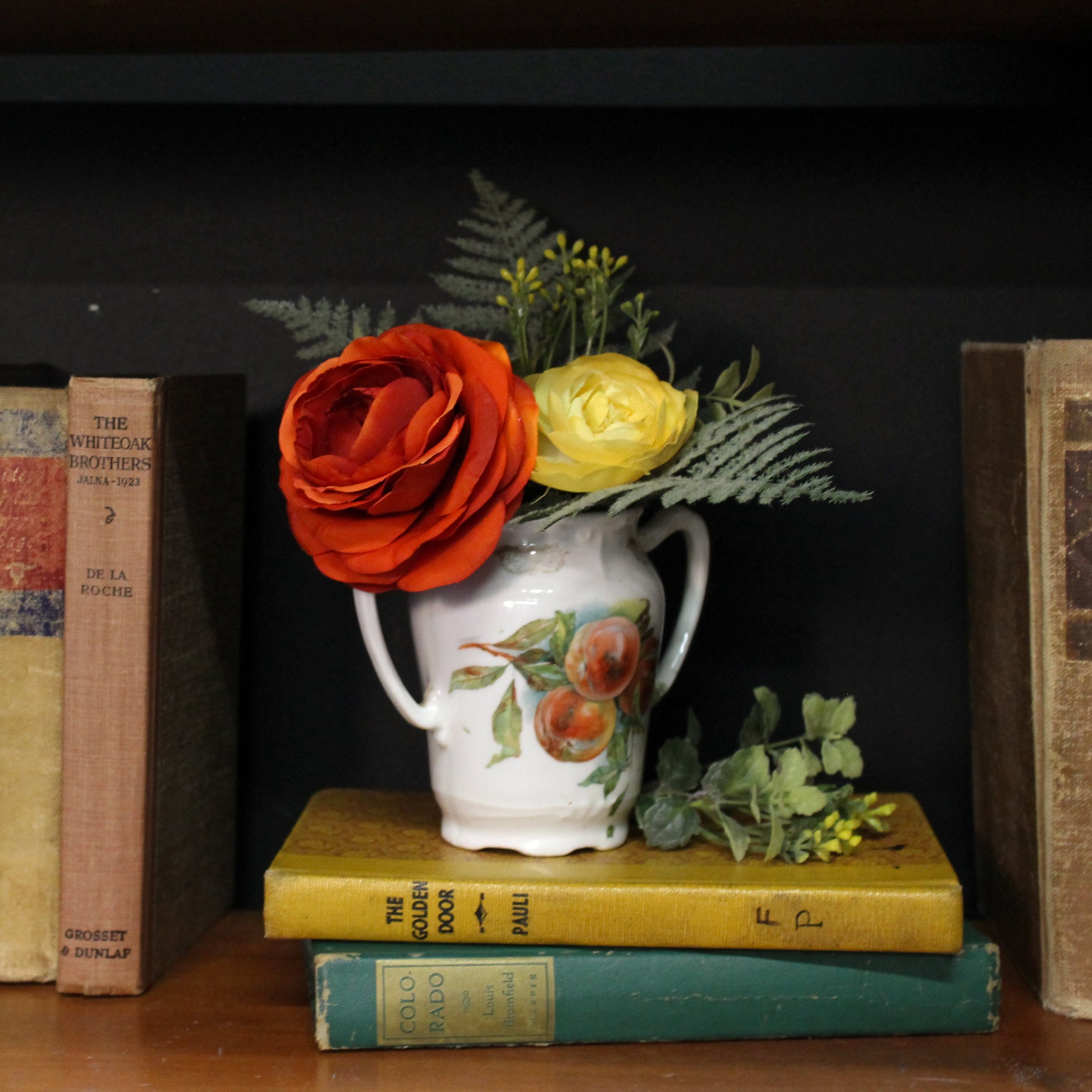 Decorative arrangement with a vase of flowers on books against a dark background