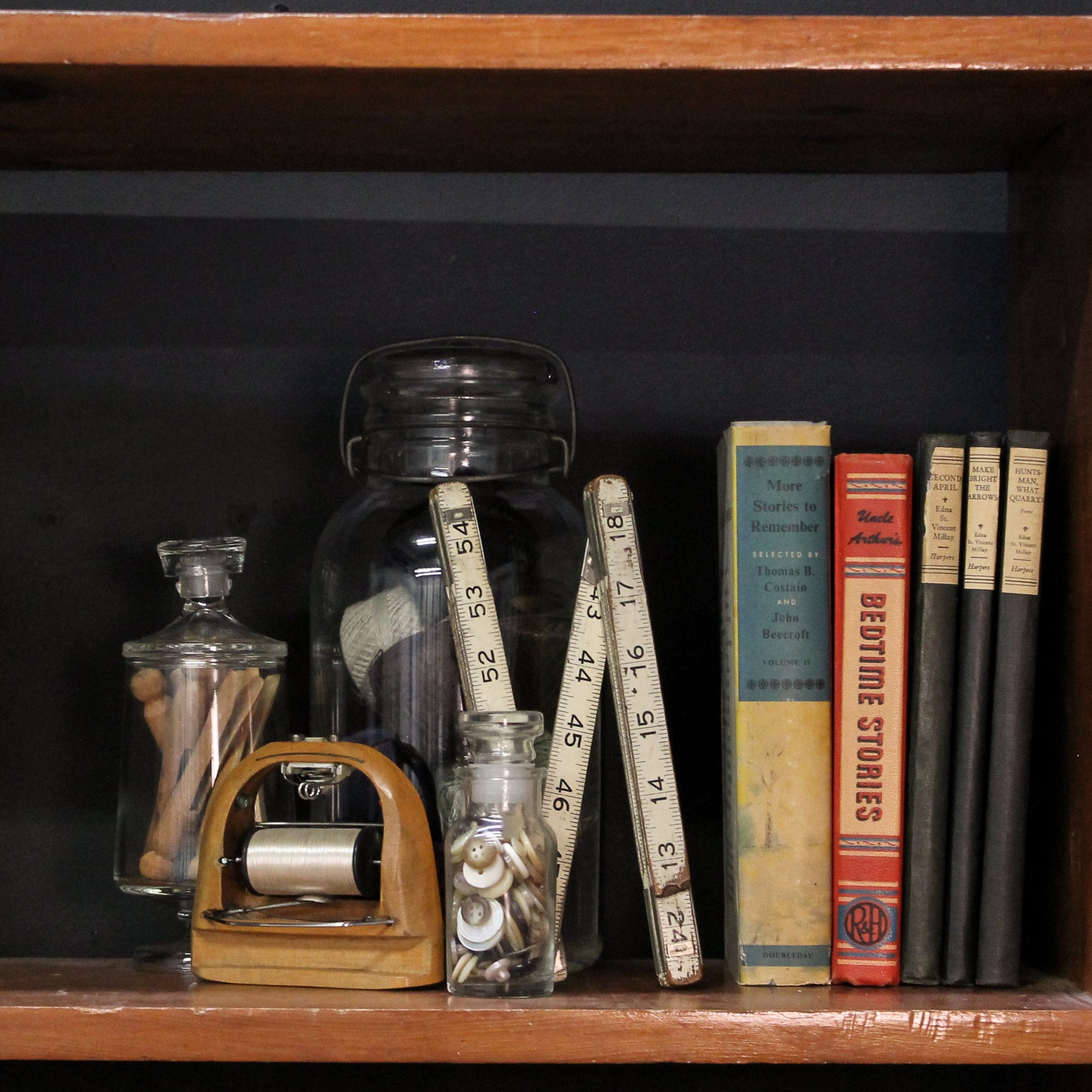 Vintage books and decorative items on a wooden shelf against a dark background