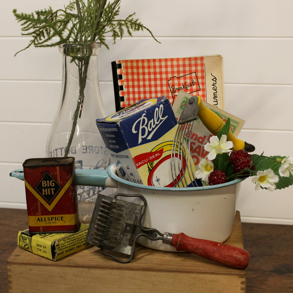 Vintage kitchen items including a can of allspice, a box of Ball brand products, and a grater on a wooden surface.