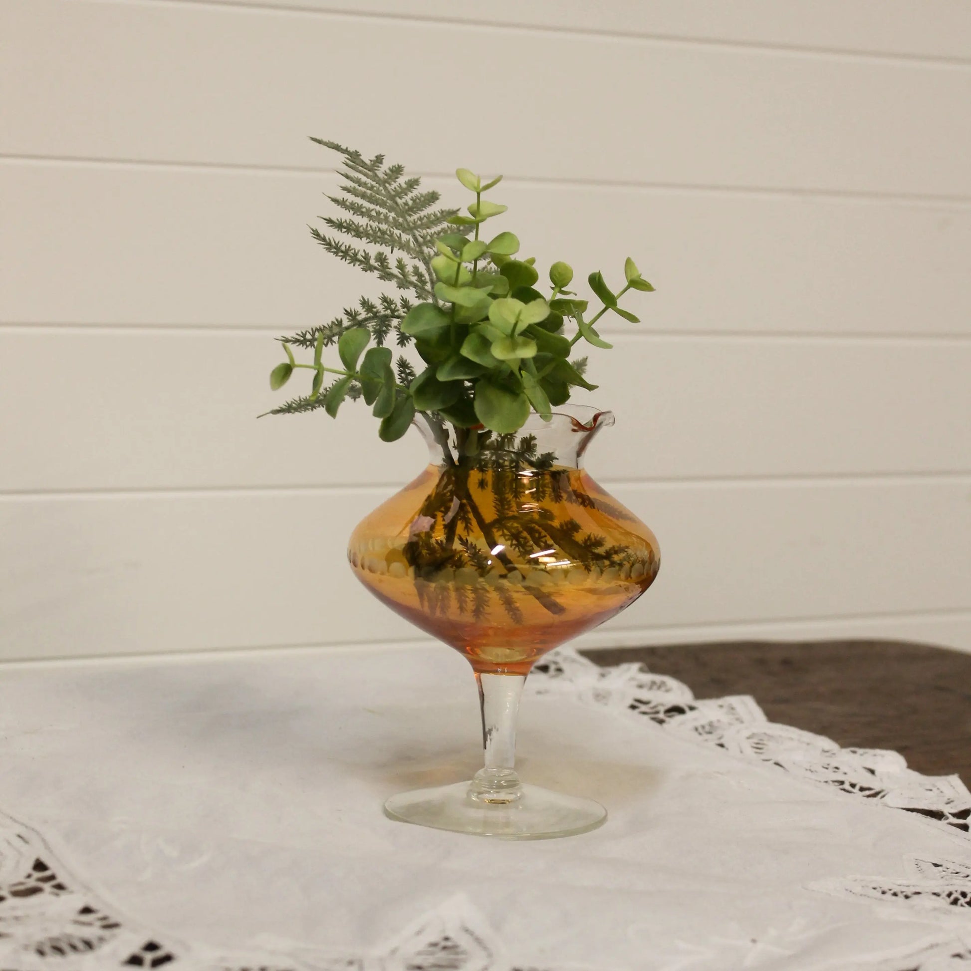 Decorative glass vase with plants on a tablecloth
