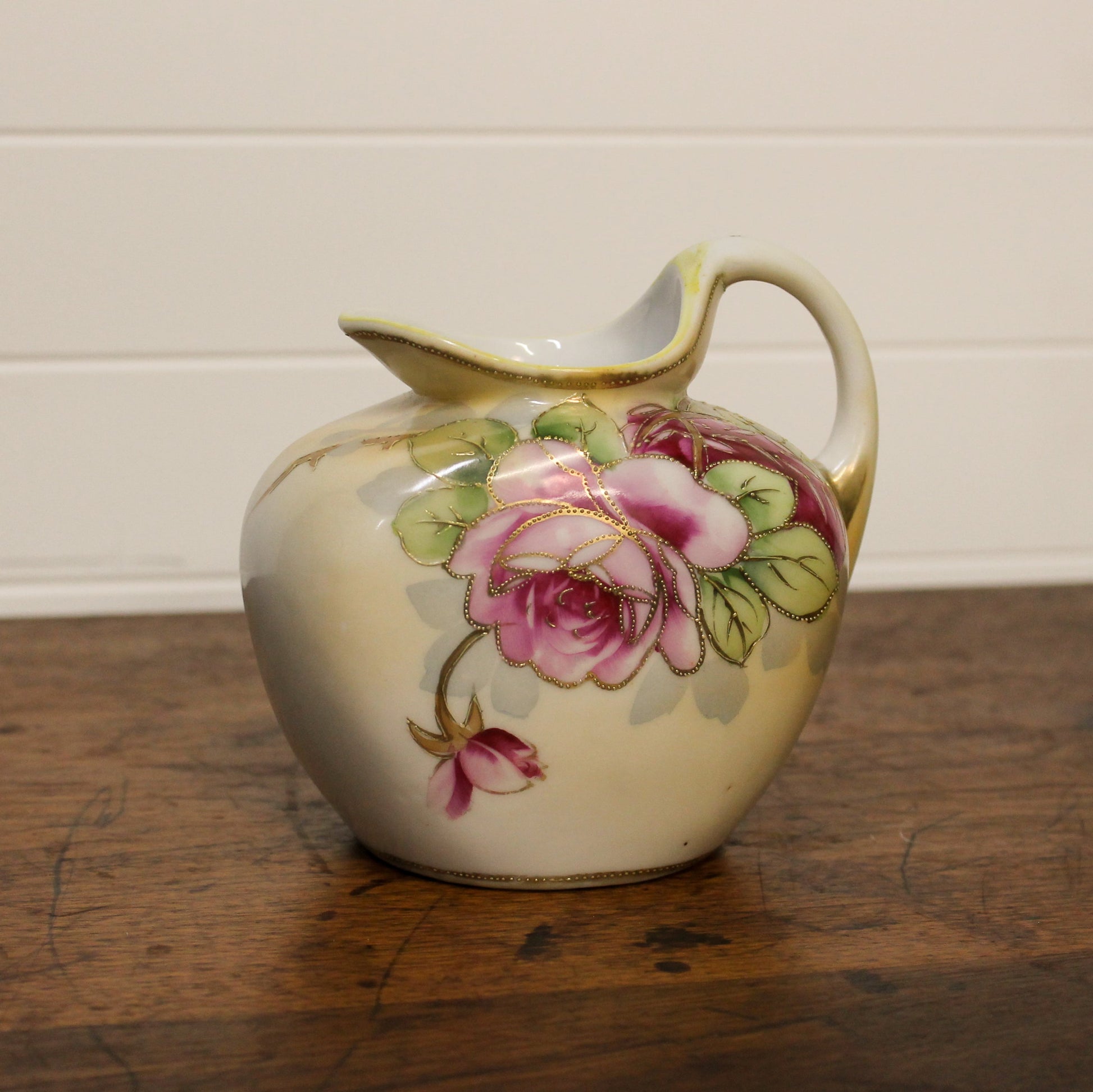 Ceramic pitcher with floral design on a wooden surface