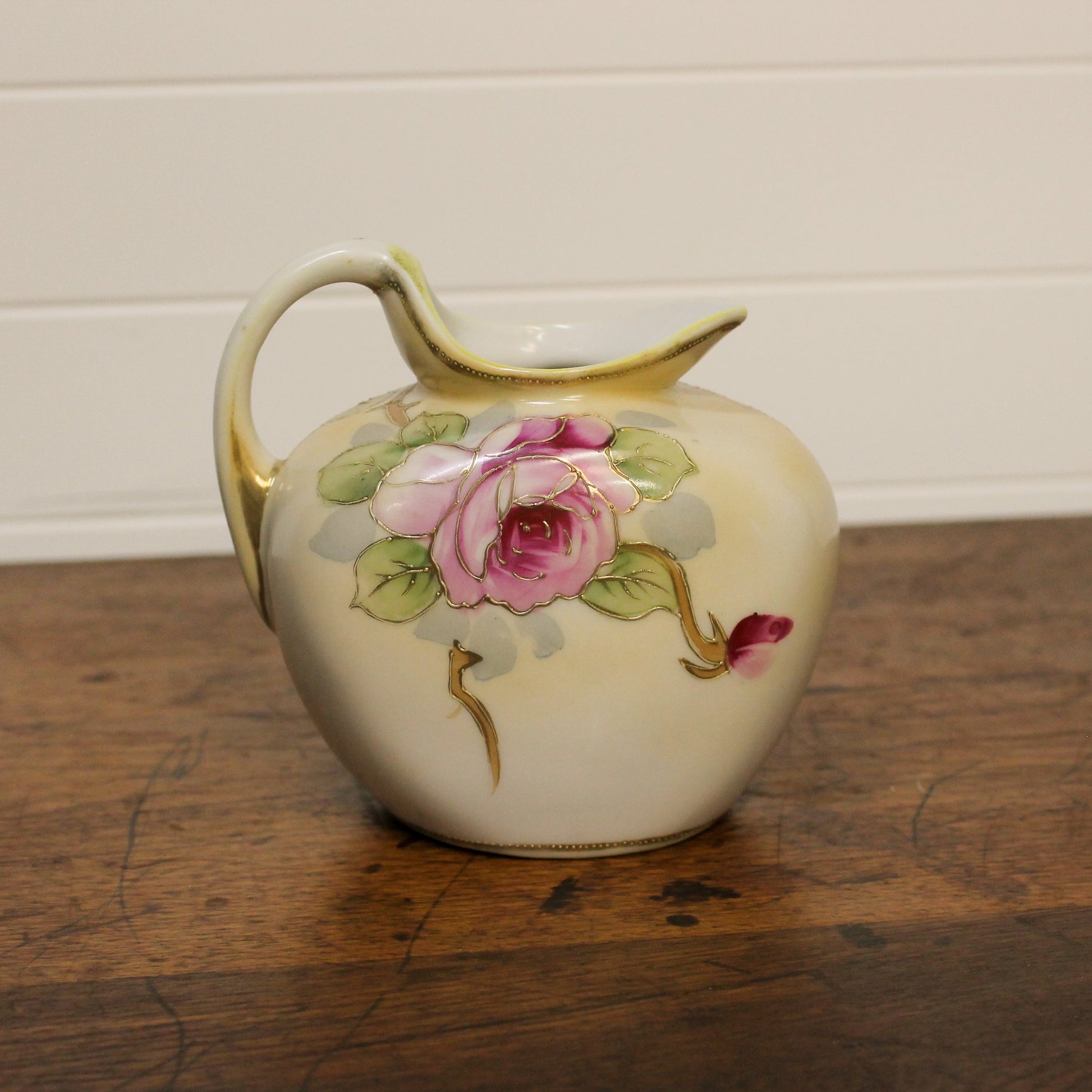 Decorative ceramic pitcher with floral design on a wooden surface