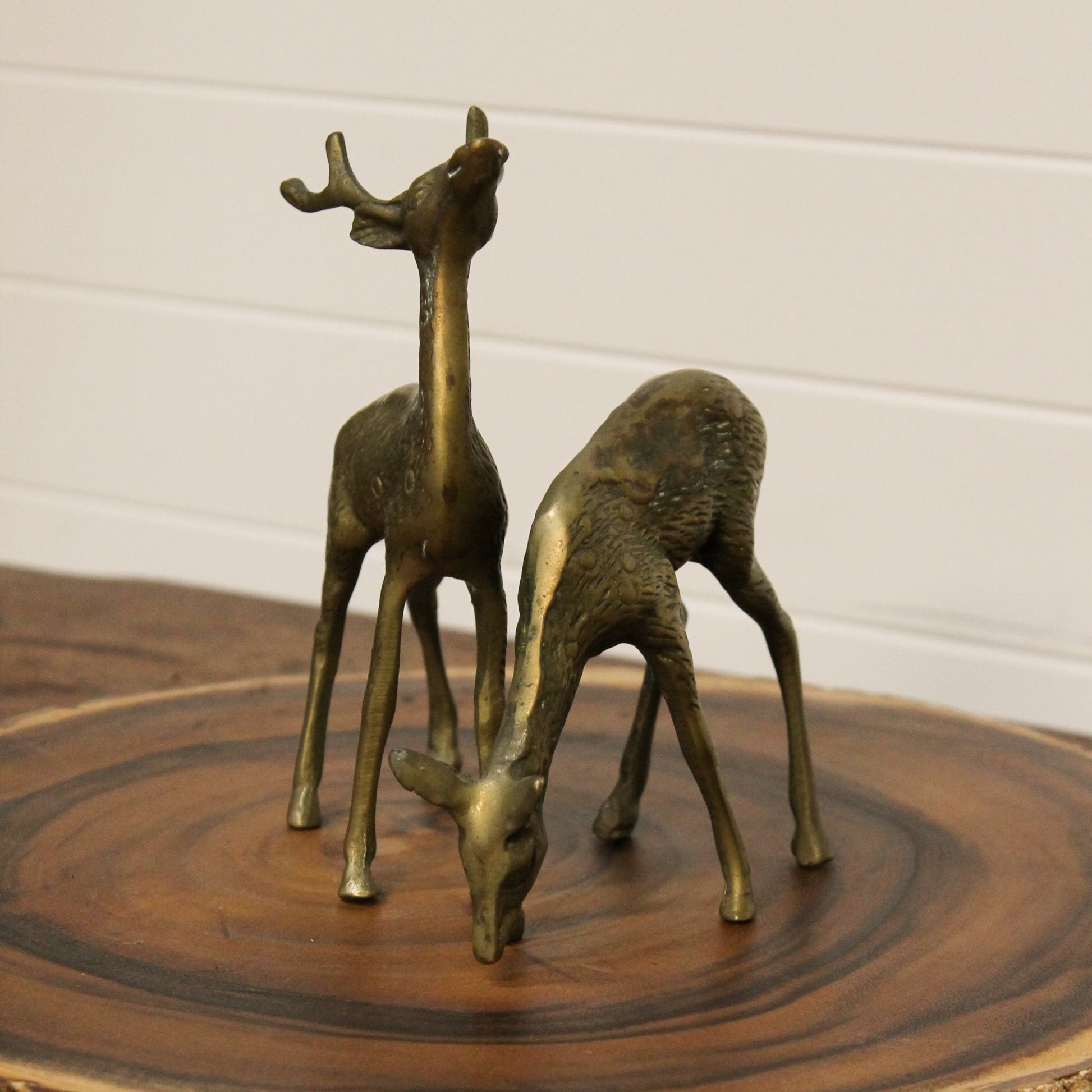 Brass deer figurines on a wooden surface with a white background